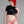 Load image into Gallery viewer, A woman with bright red hair wearing the Latex Back Zipped Cropped T-shirt by Syren Latex in black poses in front of a grey backdrop. The shirt is cropped just above her waist and has short sleeves and a round neck. She also wears pink latex panties.
