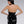 Load image into Gallery viewer, A woman with black hair poses in front of a grey backdrop, facing away from the camera. She wears the Latex Halter Top with a Zipper in black by Syren Latex. The halter top exposes the upper half of her back.
