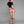 Load image into Gallery viewer, A woman with bright red hair poses in front of a grey backdrop, facing away from the camera, wearing the Cheeky Panty by Syren Latex in rose pink. She also wears the latex zip-back crop top in black, athletic-style latex knee socks and black heels.
