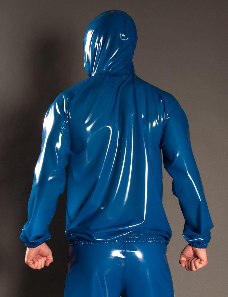 A man poses in front of a grey background, facing away from the camera. He wears blue latex pants and the Executioner Hoodie by Syren Latex in transparent blue with the hood up. 
