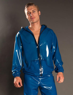 A man poses in front of a grey background wearing blue latex pants and the  Executioner Hoodie by Syren Latex in transparent blue. The hoodie is zipped up to his chest, and the hood is off.