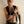 Load image into Gallery viewer, A blonde man wearing a black latex vest and no shirt poses in front of a white wall. He wears the Latex Wrist Wallet by Syren Latex in black. The wallet resembles an armband and has three metal snaps.
