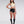 Load image into Gallery viewer, A brunette woman with red lipstick wearing the Jabot Halter Top by Syren Latex poses in front of a grey backdrop. She also wears black latex hot shorts, black latex stirrup socks, and red high heels.
