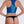 Load image into Gallery viewer, A brunette woman with red lipstick poses in front of a grey backdrop, facing away from the camera, wearing the Racer Front Tank by Syren Latex in transparent blue. She also wears a black latex thong.
