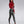 Load image into Gallery viewer, A brunette woman with red lipstick poses in front of a grey backdrop, wearing the Zeta Jacket in red by Syren Latex over a silver latex tanksuit. The jacket is cropped with an oversized collar with zipper accents. She also wears black heels.
